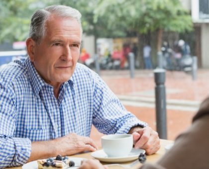 Senior couple sitting with coffee taking about Medicare