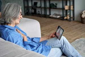Happy senior grandmother using video call to discuss Institutional Special Needs Plan.