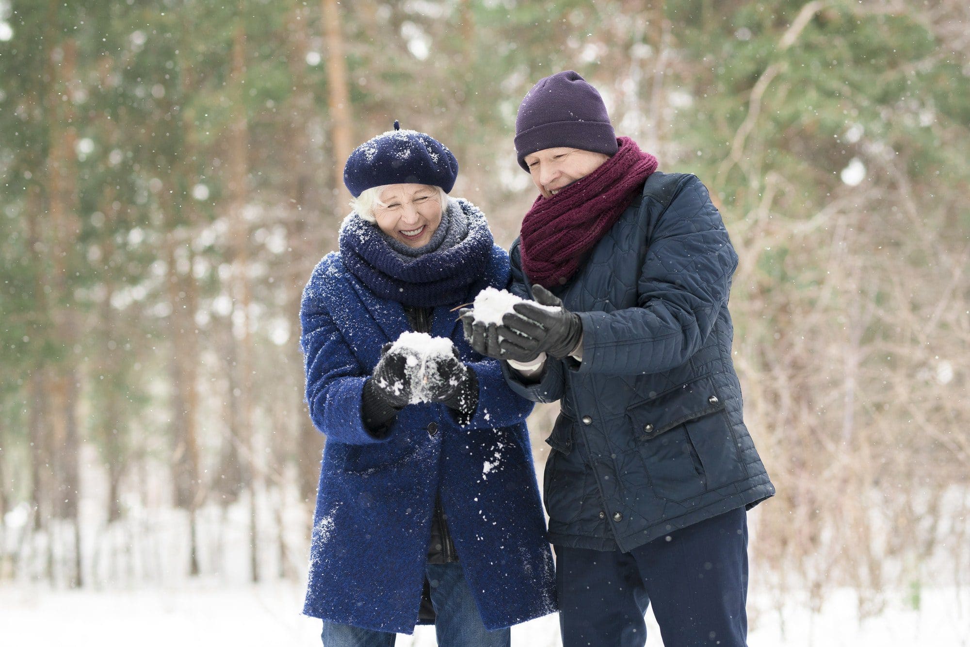 Happy couple playing in the snow as they talk about AARP and their endorsement of UnitedHealthcare
