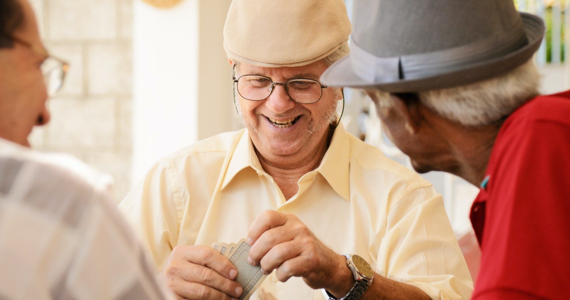 Group of happy seniors playing cards as they discuss how to get money back from their medicare on social security.